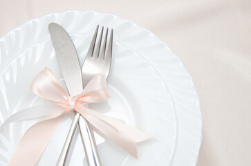 White plate, fork and knife on light background.