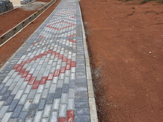 Fototapeta premium Patterned brick walkway surrounded by red soil and unfinished construction work