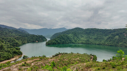 Fototapeta premium Scenic view of a lush green river bend in a mountainous landscape, ideal for concepts of tranquility and eco-tourism