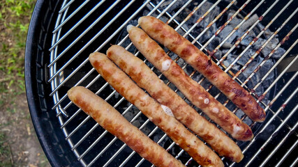 Grilled sausages cooking on a barbecue grill, perfect for summer cookouts and Fourth of July celebrations, emphasizing outdoor cooking enjoyment