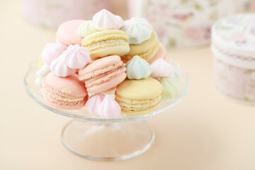 A crystal platter full of French macaroons and miniature meringues in pastel colors.