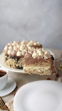 A woman takes a piece of Kyiv cake with nuts with a cake spatula