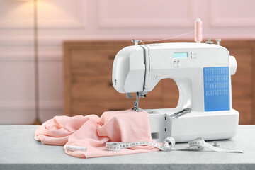 Sewing machine with fabric and other supplies on white table in workshop