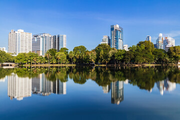Fototapeta premium Skyline of Bangkok, Thailand, viewed from Lumphini park across the lake. Reflection of skyline in the water. 