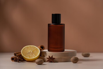 Amber glass perfume bottle on the podium with spices of cinnamon, nutmeg and citrus. Brown trendy...