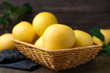 Fresh yellow apples in wicker basket on table, closeup