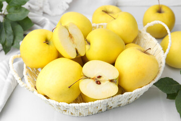 Fresh ripe yellow apples in basket on white tiled table, closeup