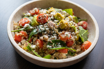 Close-up of a vibrant and nutritious salad made with quinoa, avocado, mixed seeds, and cheese,...