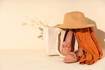 Clothes, shoes and bag on beige background, space for text