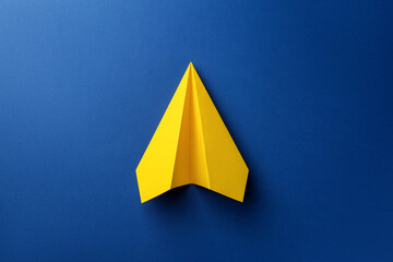 One handmade yellow paper plane on blue background, top view