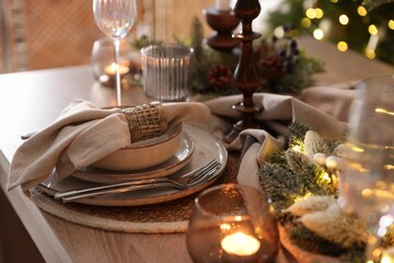 Christmas place setting with festive decor on wooden table in room, closeup