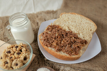 Bread with minced beef and union on a table. With white milk and snack for breakfast	
