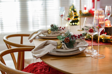 Christmas celebration. Festive table setting with dishware, glasses and decor in room, closeup