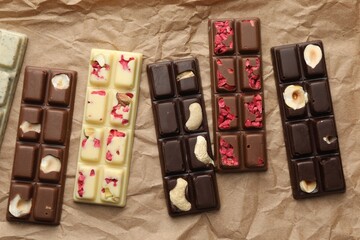 Different tasty chocolate bars on crumpled parchment, top view