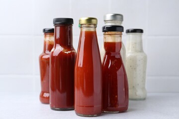 Tasty sauces in glass bottles on white table, closeup