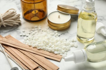 Soy wax and other supplies for making candles on white marble table