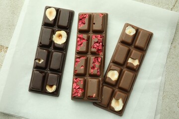 Delicious chocolate bars with different flavors on light table, flat lay