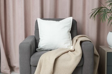 Blank soft pillow on cozy armchair at home