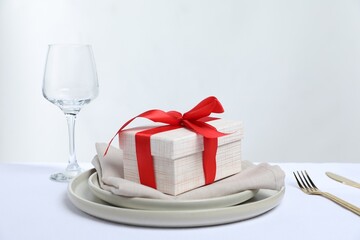 Gift and setting for romantic dinner on white background