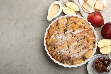 Delicious bread pudding with raisins, powdered sugar and apples on grey table, flat lay. Space for text