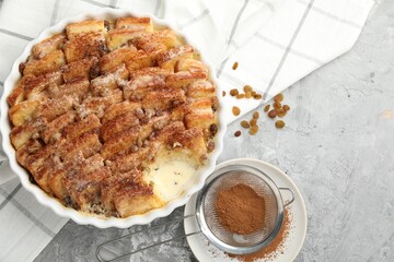 Delicious bread pudding with raisins and cinnamon on grey table, flat lay. Space for text