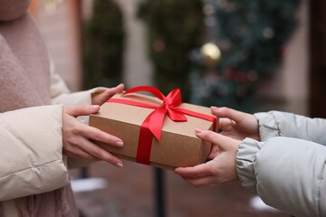 Friends with Christmas gift on city street, closeup