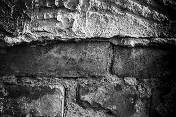 Textured wall featuring rough stone and plaster surfaces in monochrome tones