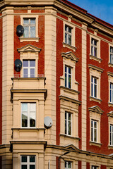 Brick apartment building with satellite dishes in urban setting under clear blue sky