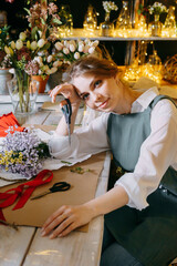A woman in her florist shop collects bouquets of flowers. The concept of a small business. Bouquets of tulips for the holiday on March 8.