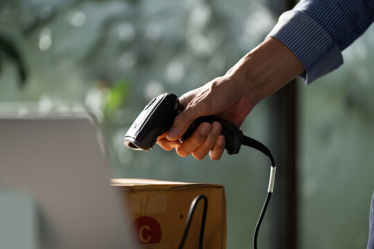 Focused small business owner using a handheld barcode scanner to process packages in a startup workspace for e-business