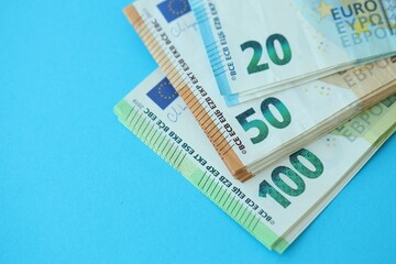 Big amount of one hundred, twenty and fifty euro money bills on blue background