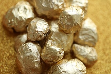 Small pile of golden nuggets on shiny gold glitter background