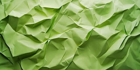 Fototapeta premium Textured green paper backdrop with various shades of green creases and folds, creating a dynamic and visually interesting surface coverage.