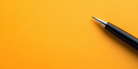 Closeup of a sleek black pen positioned at the bottom right corner of vibrant orange paper with ample blank space for writing notes or reminders