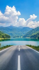 Asphalt road through the lake and mountains under blue sky with clouds