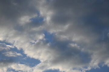 rays of the sun through cirrus clouds against a blue sky, white rainy clouds against a blue sky illuminated by the rays of the sun	
