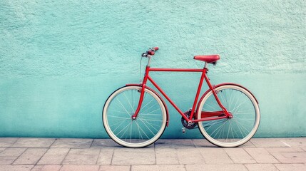 Fototapeta premium A vibrant shot of a vintage bike with a bold red frame, parked against a pastel blue wall for a trendy visual