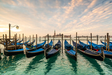 Naklejka premium Serene Sunset Over Venetian Gondolas: A Scenic View of Venice, Italy
