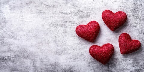 Fototapeta premium Flat lay of four textured red hearts arranged on a light gray background with ample copy space on the left for text or graphics