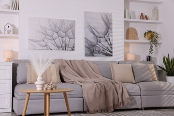 Comfortable sofa, houseplants and decorative elements in living room. Interior design