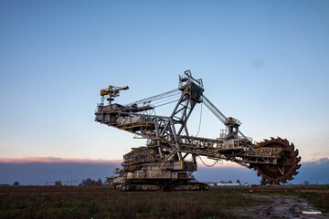 Massive bucket-wheel excavator in a field during sunset, showcasing industrial engineering