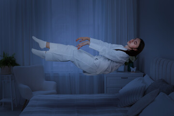 Sleepwalking. Young woman floating above bed at home, toned in blue