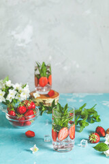 Refreshing summer drink with strawberries and mint on blue background