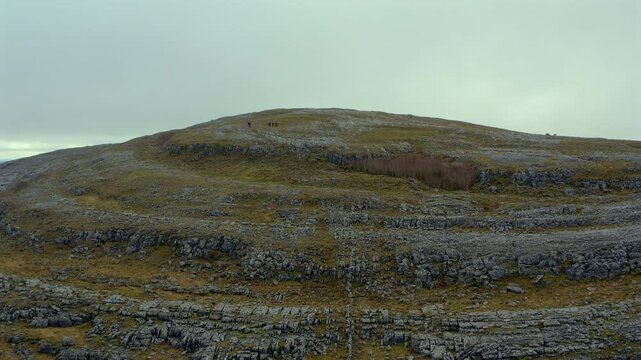 Aerial dolly approaching Mullaghmore Peak with mountaineers taking a break. Burren National Park