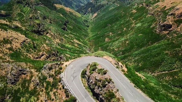 Aerial view of a scenic winding road making a hairpin turn in the lush green mountains, showcasing a breathtaking landscape, Miradouro Lombo do Mouro, Madeira, Portugal,