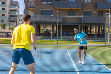 Obraz premium Two male pickleball players showing sportsmanship during training on a sunny day