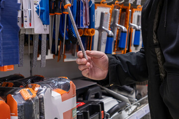man holding a diamond-coated file in a hardware store aisle with various tools on display