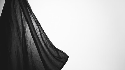 Black sheer fabric flowing with softbox lighting on a clean white photography backdrop in a minimalist studio setting