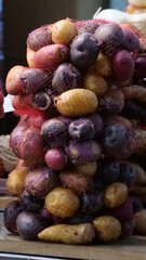 Vertical image of Potatoes of different colours in bags lying on a table close up.