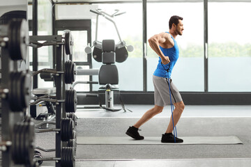 Fototapeta premium Guy with a resistance band exercising in a gym